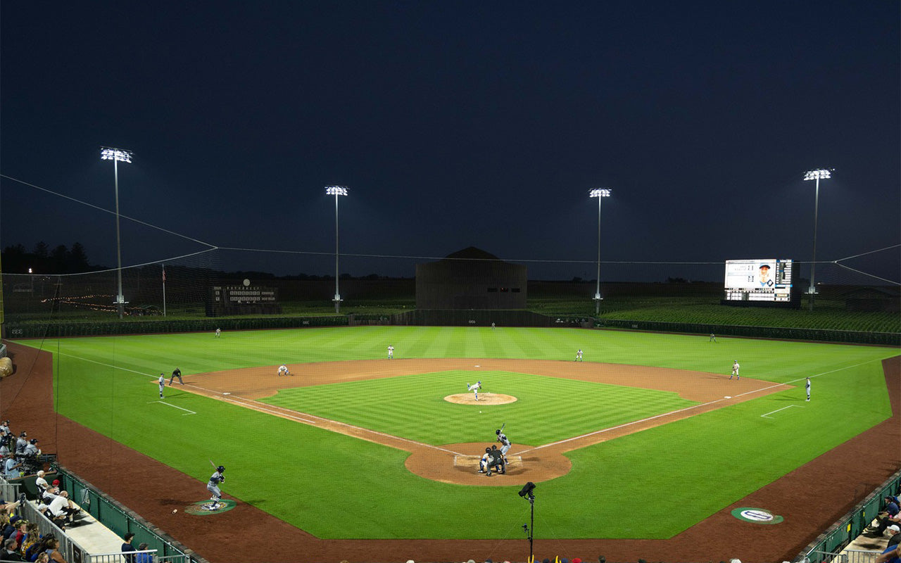 Baseball game in progress on a well-lit baseball field at night.