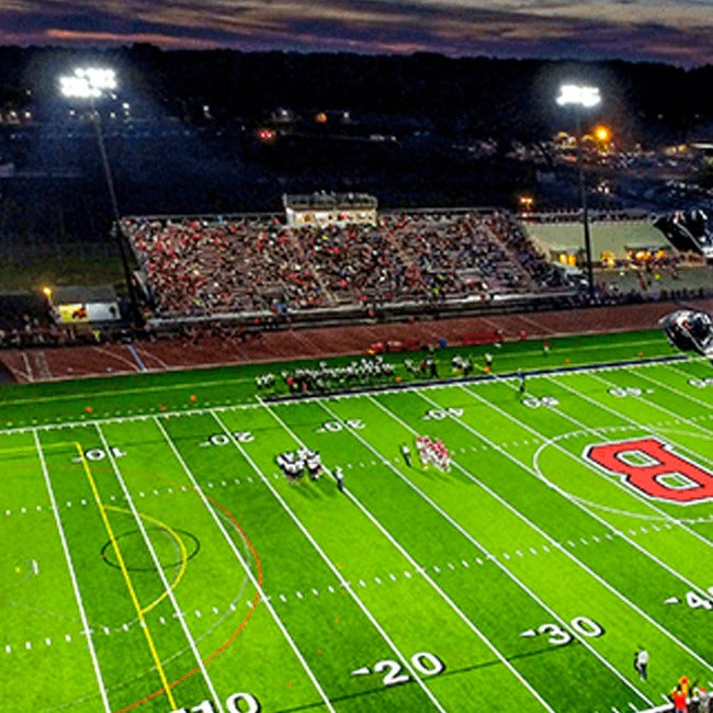 Football game in progress on a field with stadium lights and spectators.