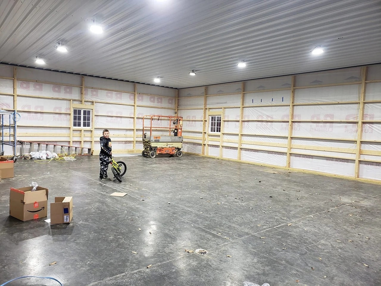 Person standing in a large, empty warehouse with concrete floor and metal walls.